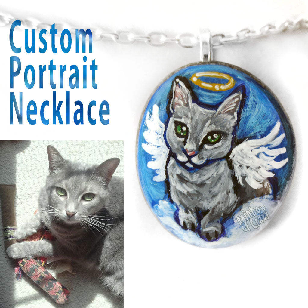 A personalized pet portrait necklace, painted on a beach stone, of a grey cat painted as an angel.