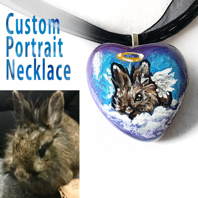 A pendant necklace created from a small beach stone, painted with a portrait of a brown lionhead rabbit as an angel. 