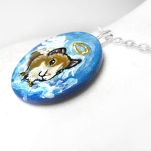 Load image into Gallery viewer, a pendant necklace, handmade from a circle wood disc, painted with a brown and white guinea pig as an angel in the blue cloudy sky
