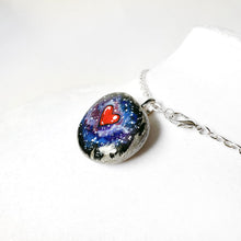 Load image into Gallery viewer, a pendant necklace, crafted from a beach stone, is hand painted with a bright red heart, surrounded by a starry galaxy sky
