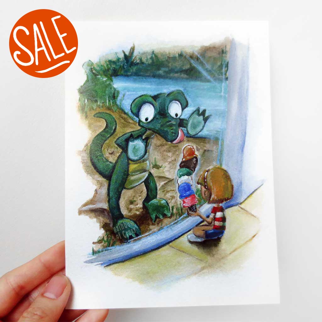 A hand holds up a 5x7 art print of an illustration: a crocodile up against the glass at the zoo, staring at the ice cream that a little girl is holding.