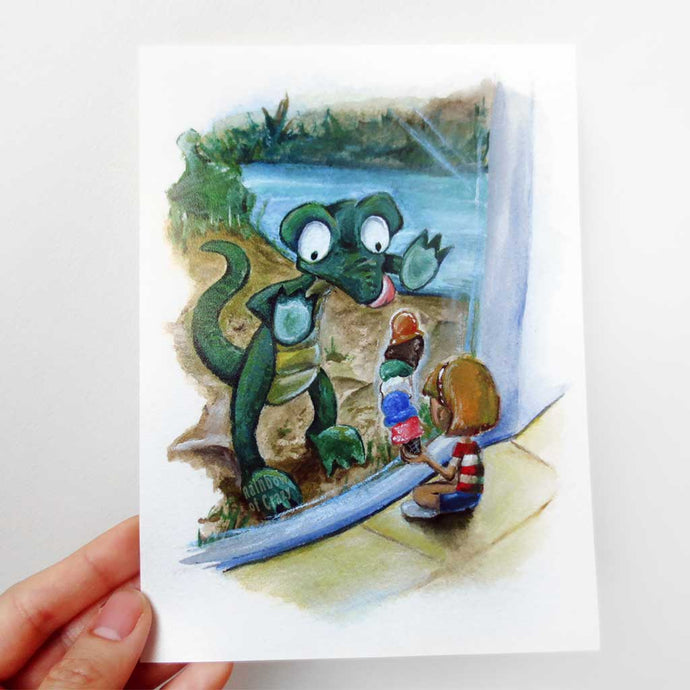 A hand holds up a 5x7 art print of an illustration: a crocodile up against the glass at the zoo, staring at the ice cream that a little girl is holding.