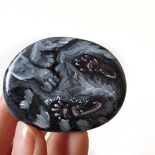 Load image into Gallery viewer, The underside of a racoon portrait, painted on a beach stone, showing its paws and tail
