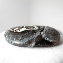 Load image into Gallery viewer, the bottom side of a beach stone, hand painted with a raccoon
