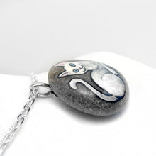 Load image into Gallery viewer, A necklace crafted from a small beach rock, featuring a pet painting of a white cat with blue eyes.
