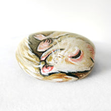 Load image into Gallery viewer, A rock painted with an albino ferret sleeping and smiling.
