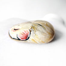 Load image into Gallery viewer, The top of a small stone painted with an albino ferret sleeping.
