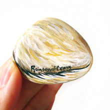 Load image into Gallery viewer, The back of a small stone painted with a portrait of a ferret, includes the shop name Rainbowofcrazy.
