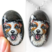 Load image into Gallery viewer, a small beach rock, hand painted with art of a smiling Australian Shepherd dog, available as a stone keepsake, fridge magnet, or pendant necklace. 
