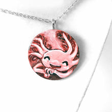 Load image into Gallery viewer, a smiling axolotl sleeping, hand painted on a circle wood disc, available as a keepsake or pendant necklace
