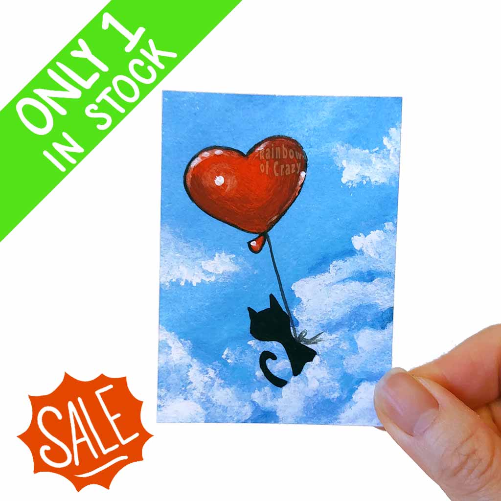 an aceo art print featuring a black cat sitting on the clouds with a red heart shaped balloon tied to its waist