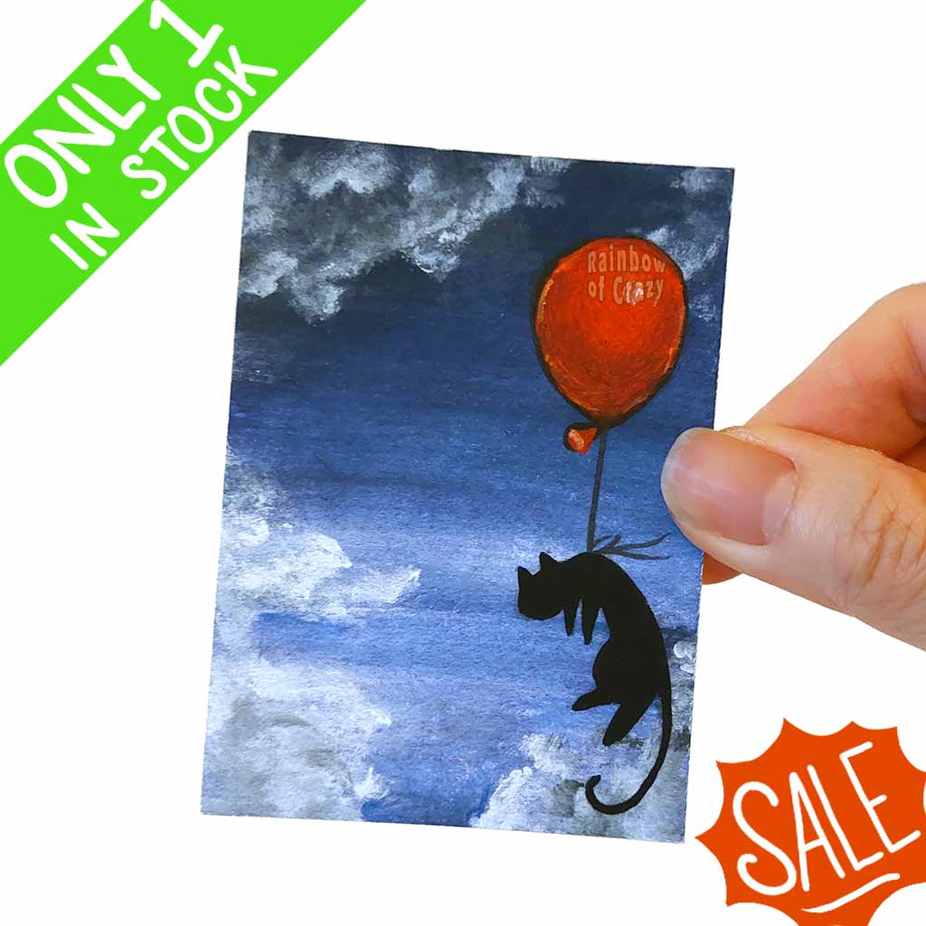 an ACEO art print featuring a black cat floating through a dark blue sky, with a big red balloon tied around its waist