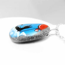 Load image into Gallery viewer, a small beach stone, hand painted with a little black cat, with a red balloon, sitting on clouds against a blue sky. available as a keepsake or pendant necklace
