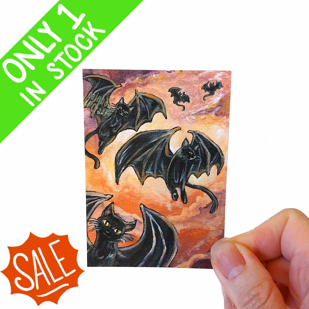 This mini ACEO print features several black cats with bat wings, soaring through an orange filled sunset sky