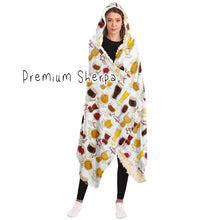 Load image into Gallery viewer, a woman wears the Beer Lovers Hooded Blanket, lined with premium sherpa: a white hooded blanket printed with a variety of different beer styles in different glasses
