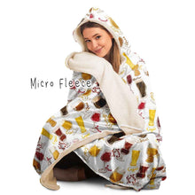 Load image into Gallery viewer, a woman wears the Beer Lovers Hooded Blanket, lined with microfiber fleece: a white hooded blanket printed with a variety of different beer styles in different glasses
