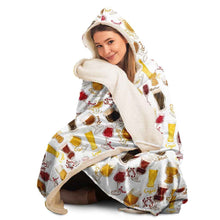 Load image into Gallery viewer, a woman wears the Beer Lovers Hooded Blanket, lined with microfiber fleece: a white hooded blanket printed with a variety of different beer styles in different glasses
