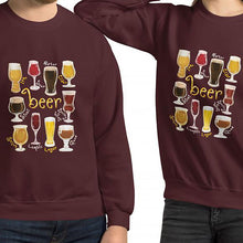 Load image into Gallery viewer, A man and woman wearing the Beer Lovers Unisex Sweatshirt in the colour maroon, featuring a graphic of 10 styles of beer in 10 different glasses
