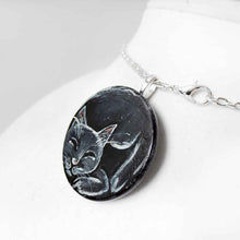 Load image into Gallery viewer, a wood circle, hand painted with a sleeping black cat, available as a keepsake or necklace pendant with chain.
