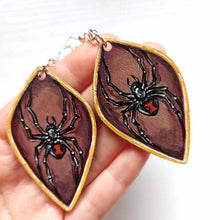 Load image into Gallery viewer, leaf shaped, wood fish hook earrings, hand painted with black widow spiders against a brown background, with a gold border
