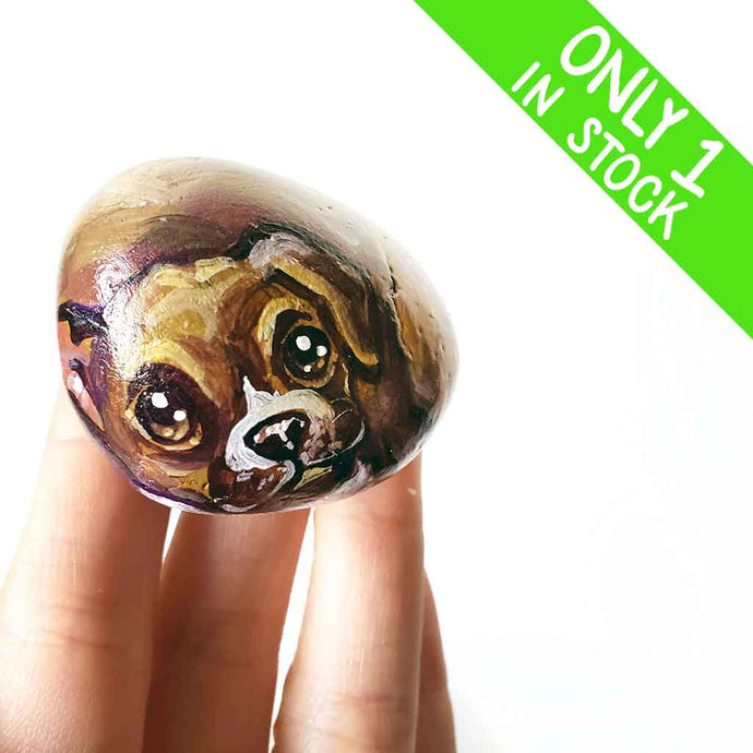 a small beach stone hand painted with a boxer dog