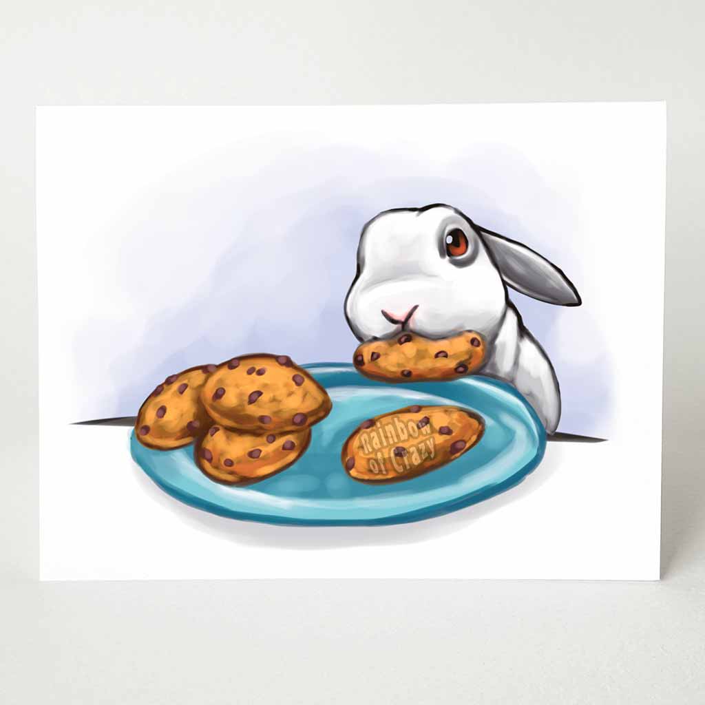 a greeting card with an illustration of a mini lop rabbit, next to a plate of cookies, with a stolen cookie in its mouth