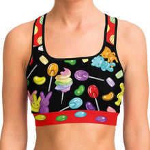 Load image into Gallery viewer, A woman wearing the Candy Lovers Sports Bra, featuring art of different rainbow candy.
