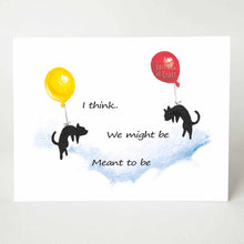 Load image into Gallery viewer, A greeting card printed with two black cats, each attached to a big balloon, floating in the sky towards each other. The text reads, &quot;We might be Meant to be&quot;
