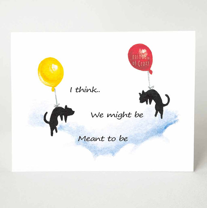 A greeting card printed with two black cats, each attached to a big balloon, floating in the sky towards each other. The text reads, 