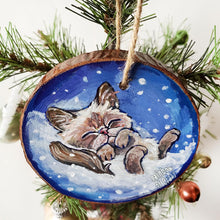 Load image into Gallery viewer, A Christmas tree wood ornament, hand painted with art of a Himalayan cat sleeping on snow.
