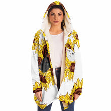 Load image into Gallery viewer, a woman wears a white microfiber fleece cloak (with pockets), printed with sunflower art, with a black cat and white cat peeking out from the flowers
