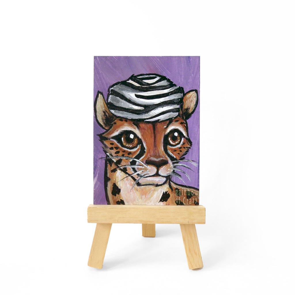 An ACEO original painting with a portrait of a cheetah wearing a zebra print fur hat