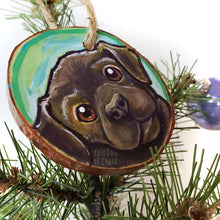 Load image into Gallery viewer, A wood Christmas ornament, hand painted with art of a brown labrador dog with reddish brown eyes
