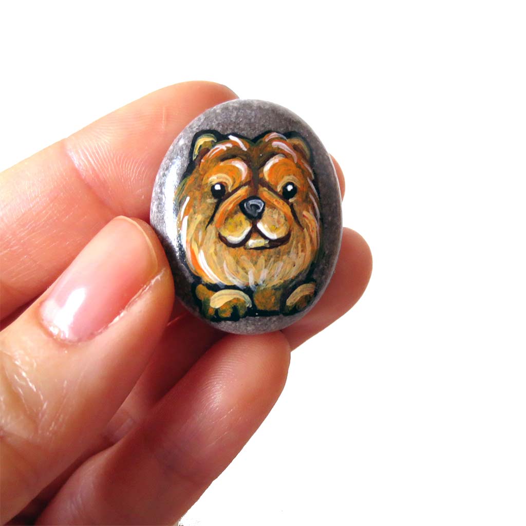 a small stone painted with the portrait of chow chow dog, available at a keepsake or necklace.