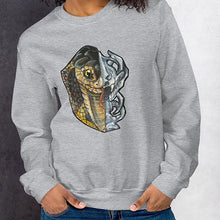 Load image into Gallery viewer, A woman is wearing a unisex sweatshirt in the colour sport grey, printed with an illustration split into two: the left side features the face of a cobra snake, and the right side features an evil looking snake skull.
