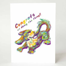 Load image into Gallery viewer, a greeting card featuring a dog catching her own tail, painted with rainbow colours. above reads, congrats on doing the thing!!
