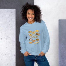 Load image into Gallery viewer, A woman wearing the Cookie Lovers Unisex Sweatshirt in the colour light blue, which features an illustration of 10 types of cookies
