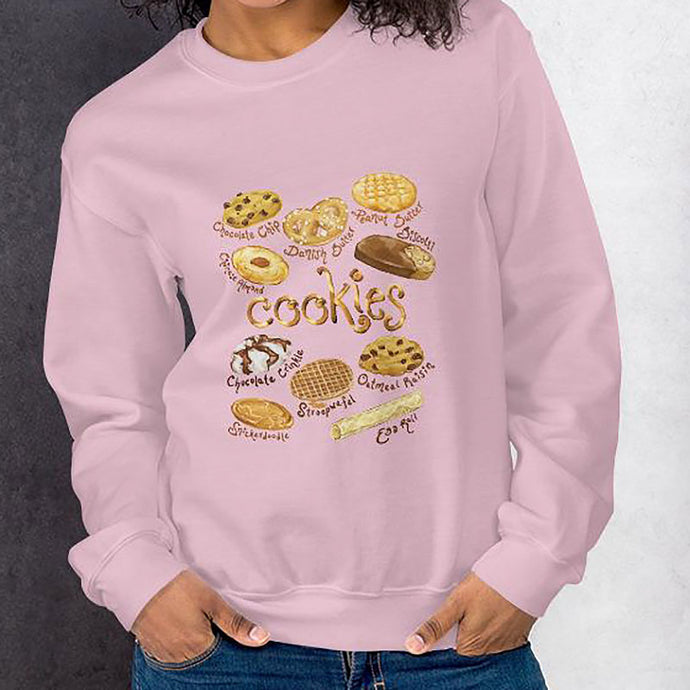 A woman wearing the Cookie Lovers Unisex Sweatshirt in the colour light pink, which features artwork of 10 types of cookies