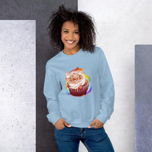 Load image into Gallery viewer, A woman wears a unisex sweatshirt in the colour light blue, featuring artwork of a cat painted as a red velvet cupcake with rainbow sprinkles.
