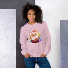 Load image into Gallery viewer, A woman wears a unisex sweatshirt in the colour light pink, featuring a print of a cat painted as a red velvet cupcake with rainbow sprinkles.
