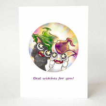 Load image into Gallery viewer, A greeting card with art of a black cat with a green witch hat, and a white cat with a purple witch hat, staring adoringly at the viewer with stars in their eyes. The card reads, Best witches for you!
