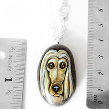 Load image into Gallery viewer, a small beach stone, hand painted with a portrait of an Afghan Hound dog, available as a keepsake stone or necklace. 
