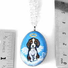 Load image into Gallery viewer, a small beach stone hand painted with a brown and white Springer spaniel dog as an angel sitting on clouds. available as a keepsake or pendant necklace
