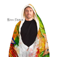 Load image into Gallery viewer, a man is wearing the Autumn Fairy Cats Hooded Blanket with microfleece lining, featuring art of a white/orange  cat, and black/blue cat, each with leaf wings
