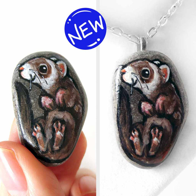 a small beach stone, hand painted with a portrait of a smiling ferret, available as a keepsake rock art, or pendant necklace