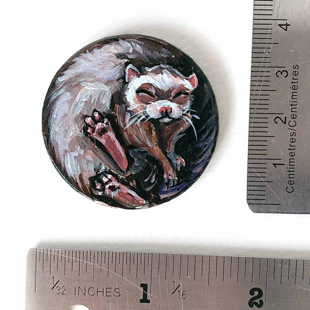 a ferret sleeping, hand painted on a circle wood disc, available as a keepsake or pendant necklace