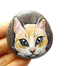 Load image into Gallery viewer, Rock art featuring the face of a flame point siamese cat with orange and white fur and grey blue eyes
