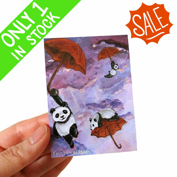 an aceo featuring art of three panda bears flying through the sky, each holding a red umbrella