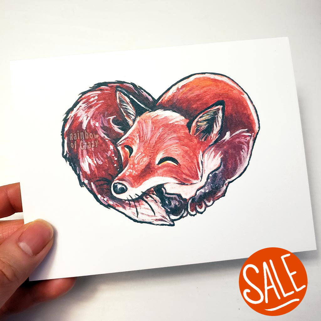 a greeting card featuring an illustration of a red fox sleeping, forming the shape of a heart.