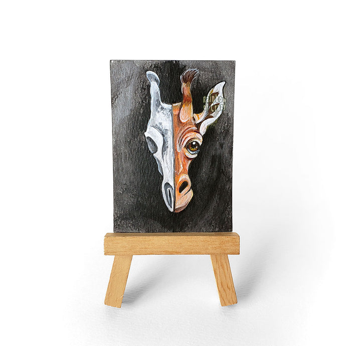 An original ACEO painting features a split portrait of a giraffe's face on the right, and its creepy skull on the left.